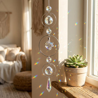 Decorative crystal hanging on a window sill with a potted plant and blurred living room background