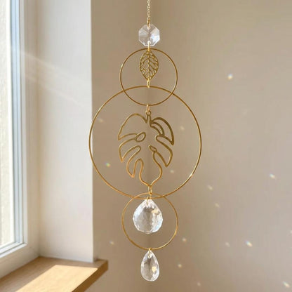 Decorative hanging crystal with gold leaf and teardrop shapes in a room with natural light.