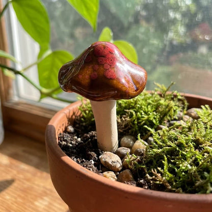 Mushroom-shaped decorative item in a pot with moss and stones on a windowsill.