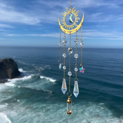 Decorative hanging ornament with celestial design against a blue sky and ocean background