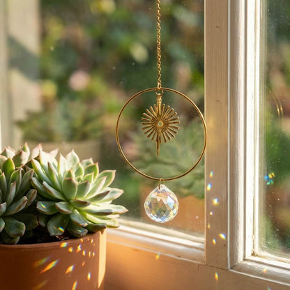 Decorative sun catcher with crystal pendant hanging by a window with plants.