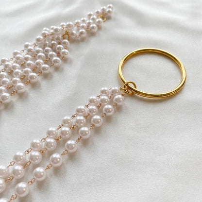 Pearl necklace with a gold ring on a white background