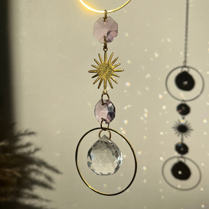 Decorative hanging with crystals and sun design on a neutral background
