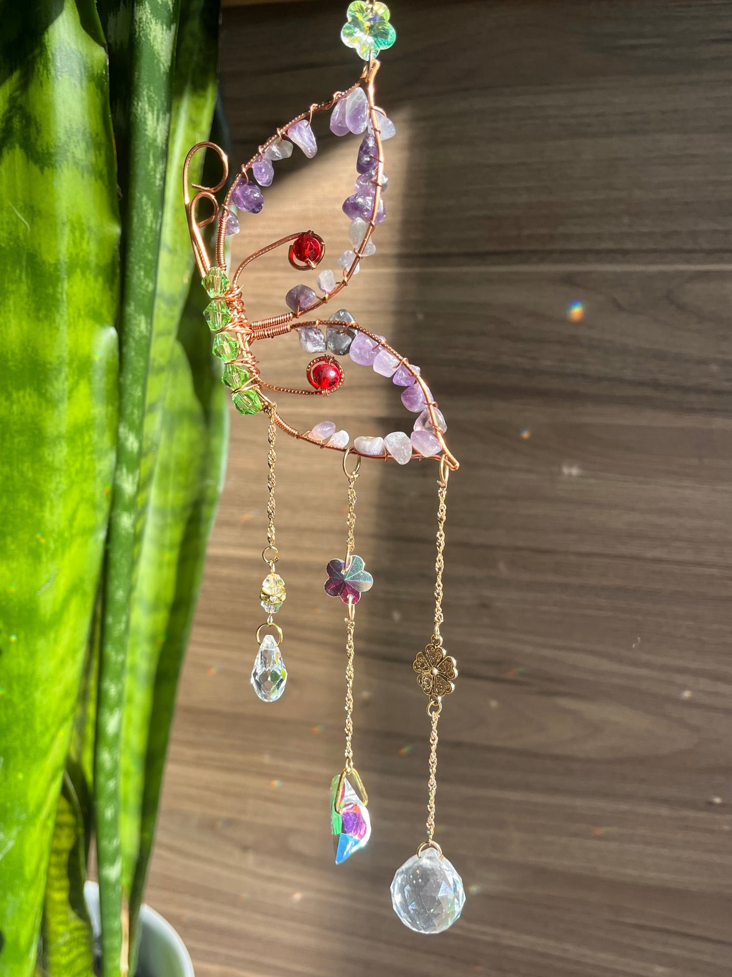 A decorative wind chime with amethyst and red agate butterfly silhouettes, suspended by a chain of beads.