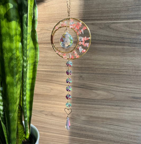 A hanging dreamcatcher featuring a pink moon and rose quartz with decorative beads in various colors.