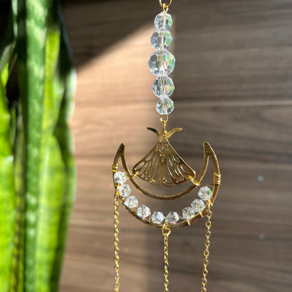 Decorative hanging ornament with crystals and gold elements against a wooden background