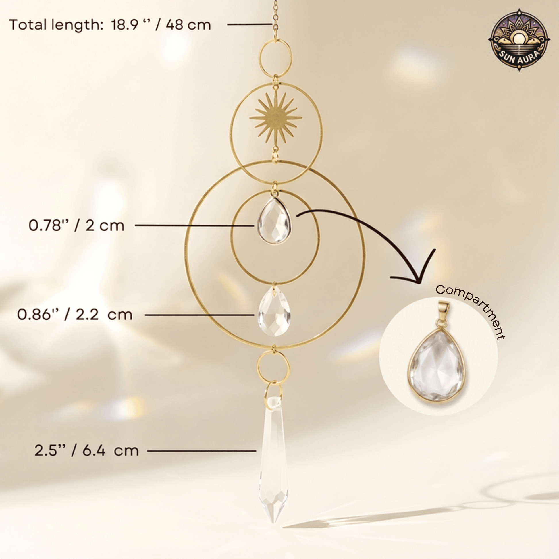 Gold-toned suncatcher with clear teardrop and crystal pendants, shown with measurement callouts and a inset detail of the compartment. The Sun Aura brand logo appears in the top right.