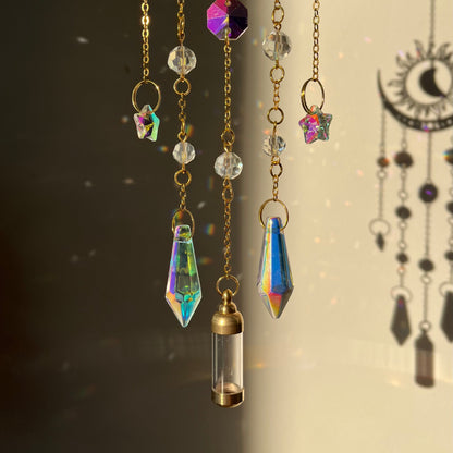 Decorative hanging chains with crystals and a small gold pendant on a dark background.