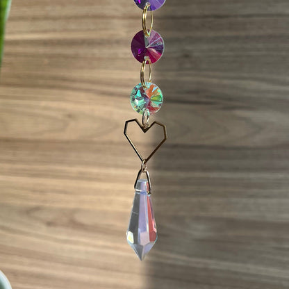 Decorative hanging crystal with colorful beads on a wooden surface