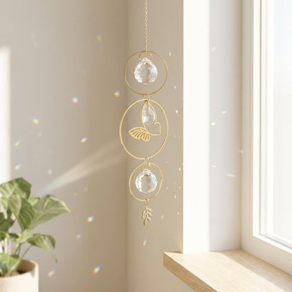 Decorative hanging crystal with gold frame in a bright room with a plant.