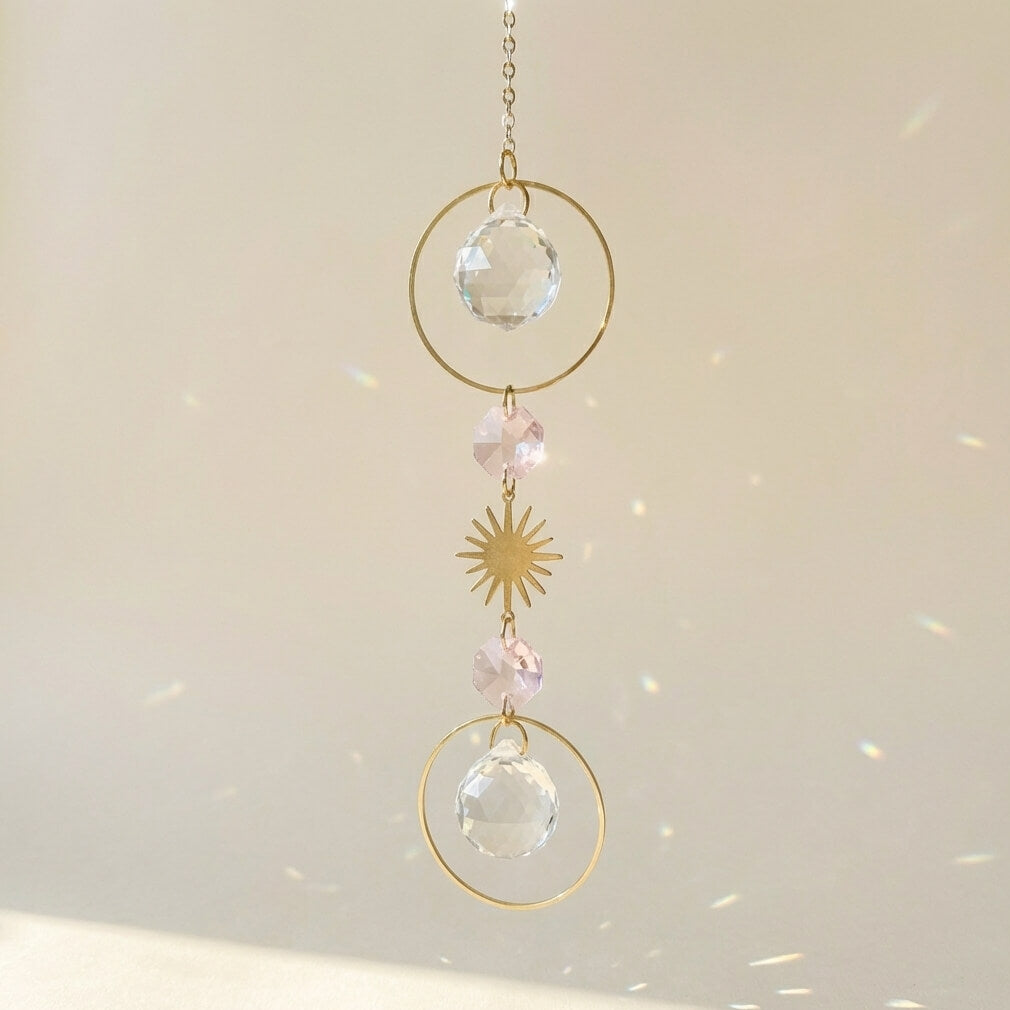 Decorative hanging crystal with gold loops and beads on a light background
