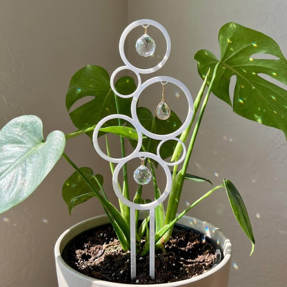 Decorative plant stake with circular design and crystal-like elements in a pot.