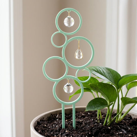 Decorative plant stand with hanging crystals next to a potted plant.