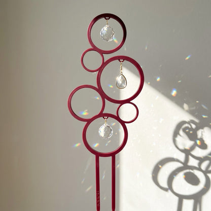 Decorative sun catcher with red circular design and crystal beads on a plain background