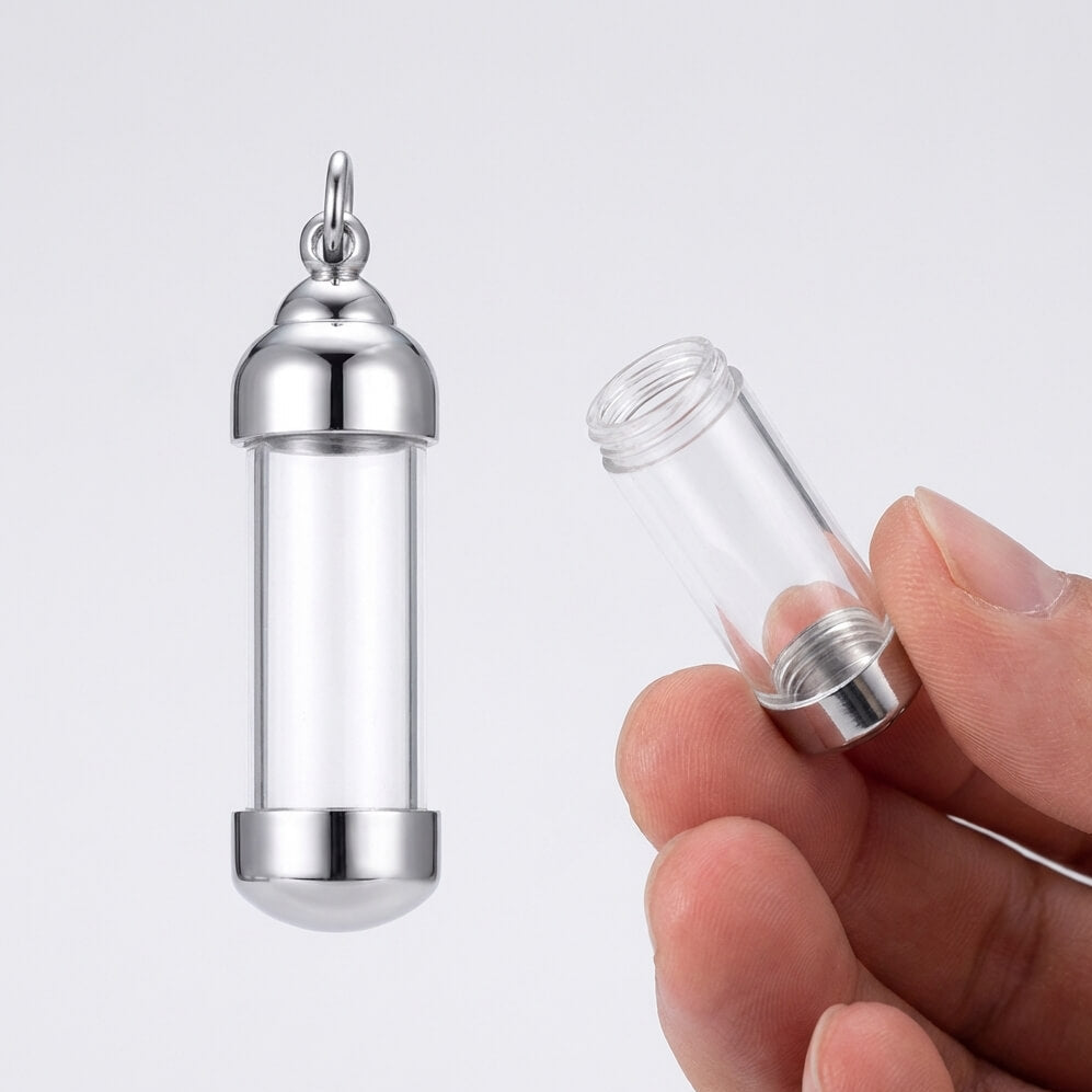 Silver and clear glass pendant held by a hand against a white background