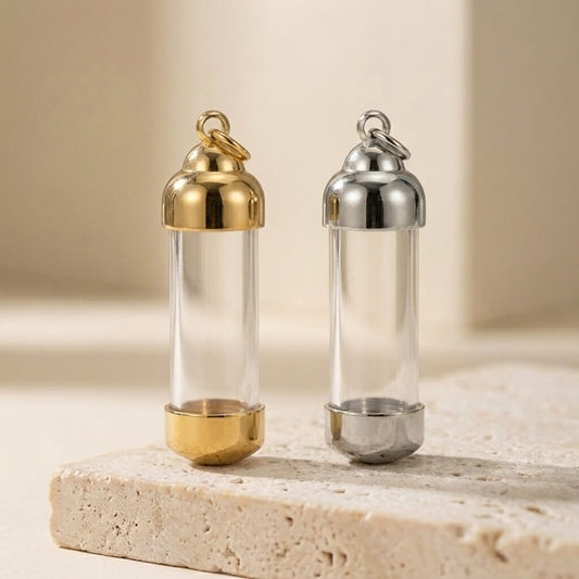 Two clear cylindrical containers with gold and silver lids on a beige surface.